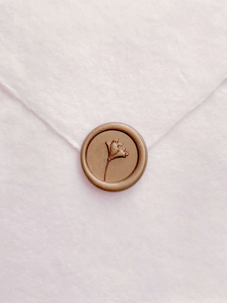 Gold mini flower wax seal on a white handmade paper envelope