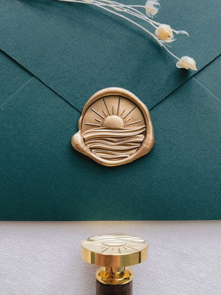 3D sunrise over ocean waves gold wax seal on a dark green envelope