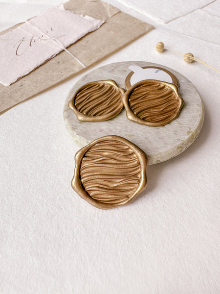 Ocean waves gold wax seals with 3D engraving styled with a small gray stone dish, handmade paper and a dried floral branch