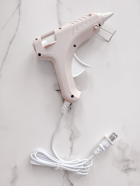 Beige low-temperature glue gun on white marble pattern backdrop