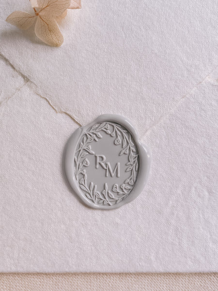 Oval floral crown monogram wax seal in light gray on white handmade paper envelope
