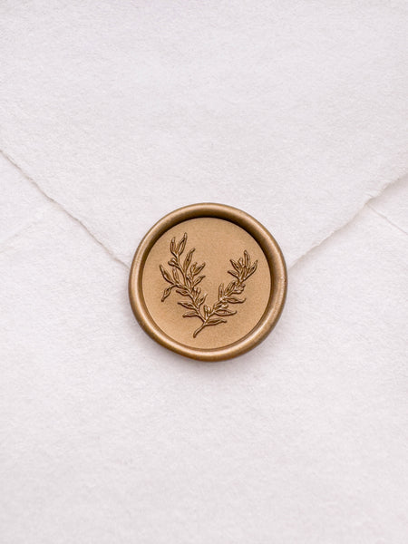 gold botanical leaf design wax seal on a white envelope