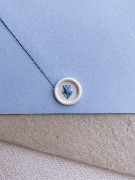 white and blue 3D flower emoji mini wax seal on a blue envelope