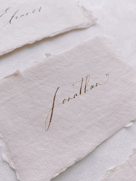 handmade paper place card in light cream color hand lettered in modern calligraphy in brown ink_close up