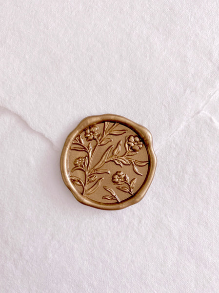 Floral gold wax seal on a white handmade paper envelope