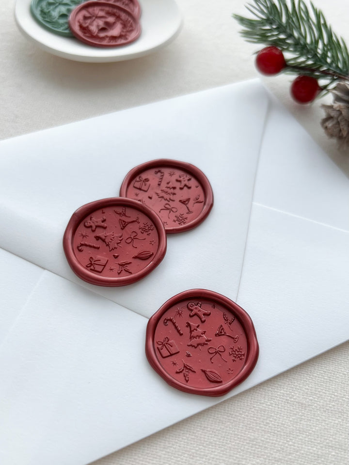 three red wax seals featuring a Christmas design of festive holiday symbols like Christmas tree, candy cane, gingerbread man, snowflakes, presents, and more