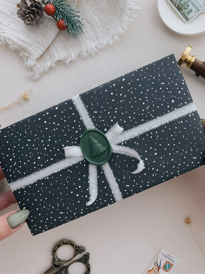 Dark green oval 3D Christmas tree wax seal on a wrapped holiday gift