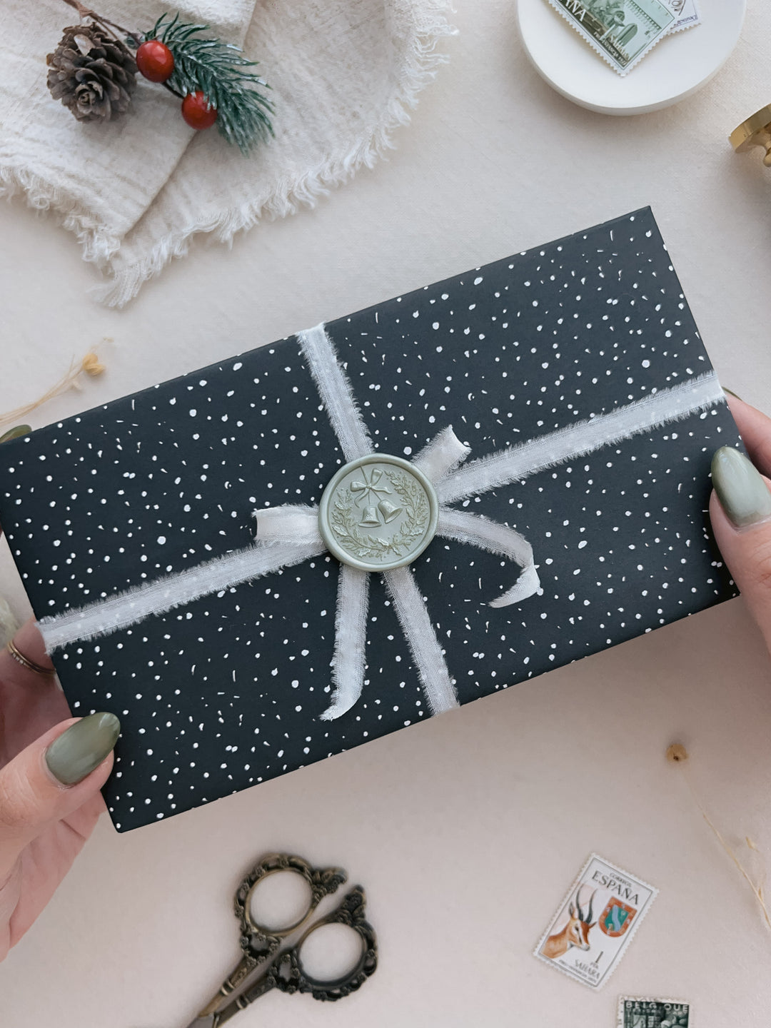 Light metallic green festive Christmas wreath wax seal on a wrapped Christmas gift