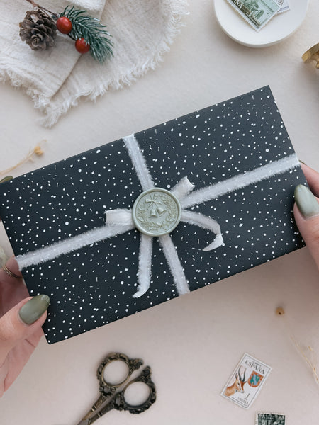 Light metallic green festive Christmas wreath wax seal on a wrapped Christmas gift