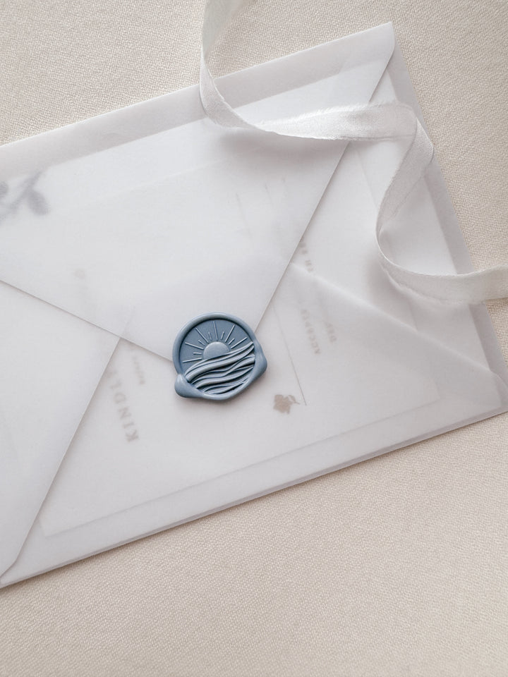 Dusty blue 3D sunset and ocean wax seal on a vellum wedding invitation envelope