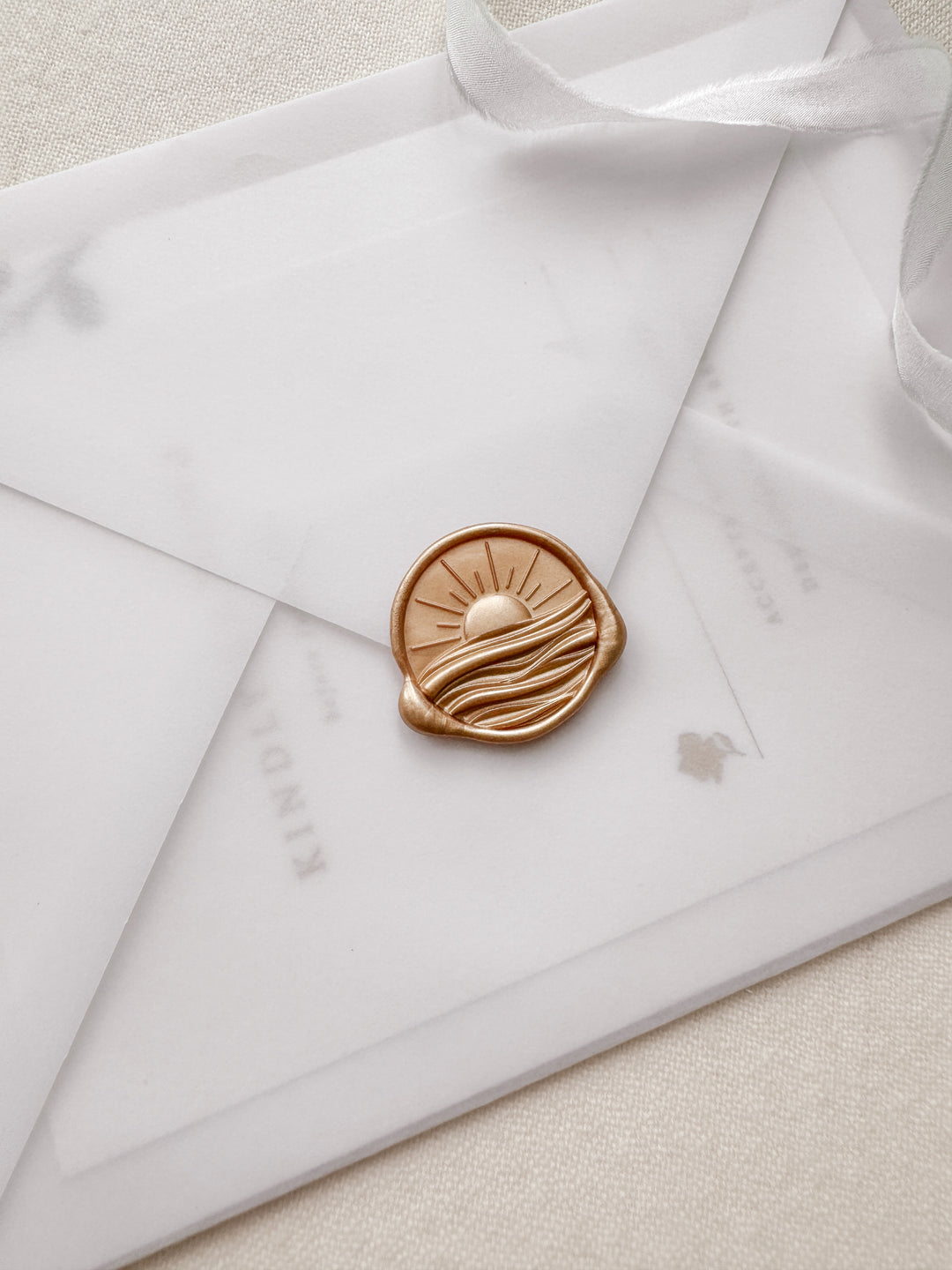 Orange gold 3D sun ray over ocean waves wax seal on a vellum wedding invitation envelope 