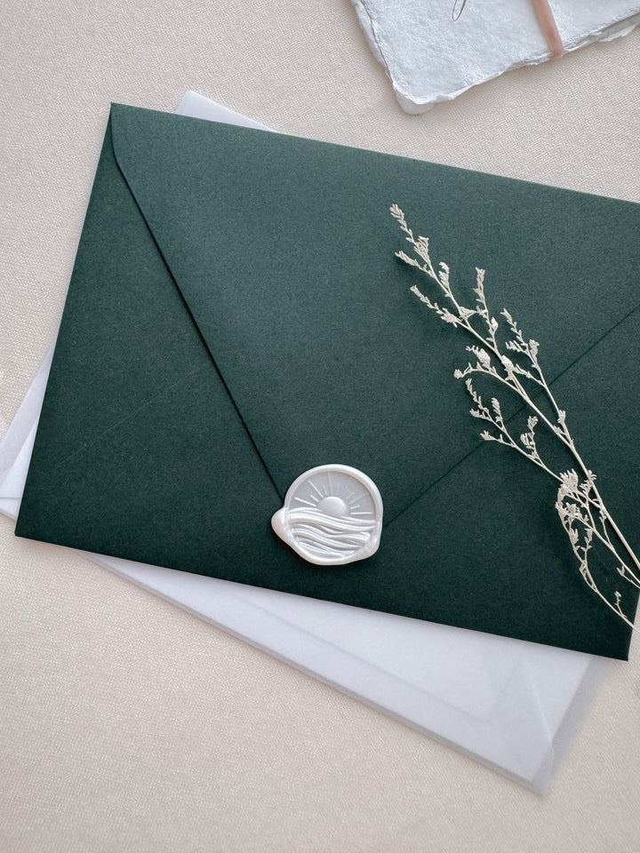 Pearl white 3D sun and ocean waves wax seal on a dark green envelope