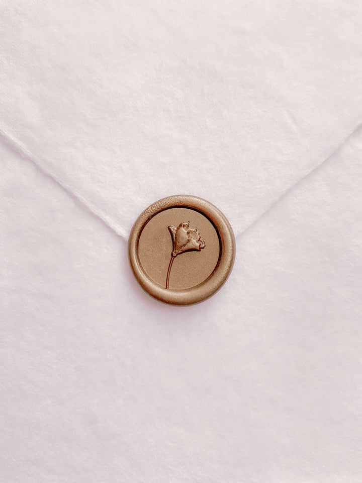 Gold mini flower wax seal on a white handmade paper envelope