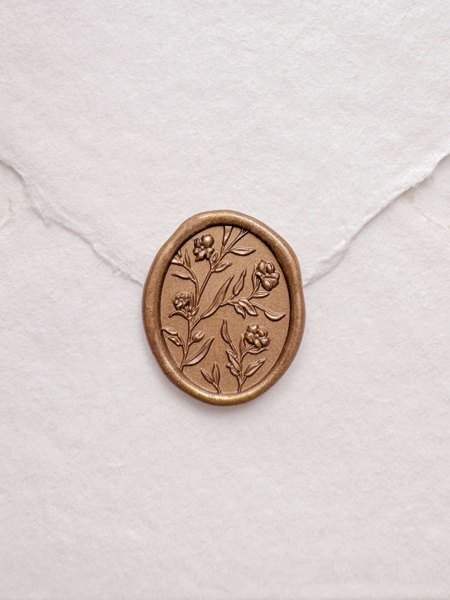 Floral pattern oval gold wax seal on a white handmade paper envelope