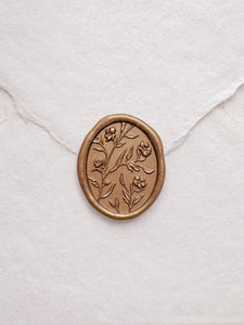 Floral pattern oval gold wax seal on a white handmade paper envelope