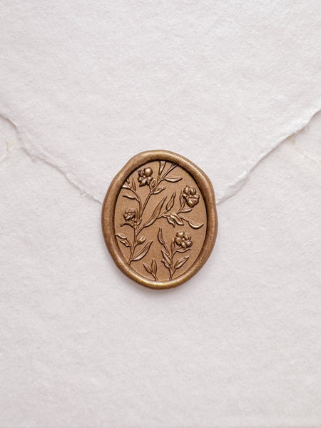 Floral pattern oval gold wax seal on a white handmade paper envelope