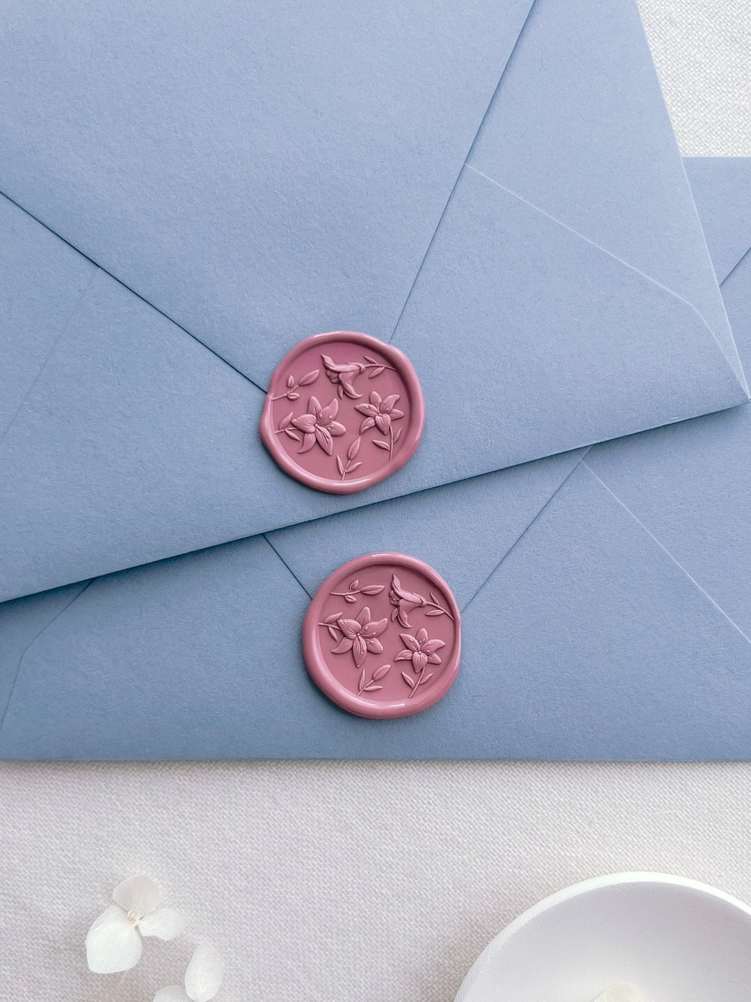 two rose pink 3D lilies wax seals on two dusty blue envelopes