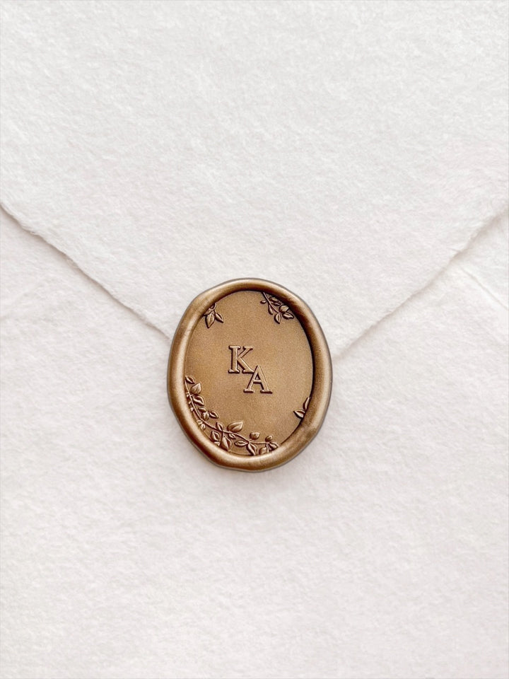 Personalized initials botanical oval gold wax seal featuring personalized initials framed by 3D engraved leaves on a white handmade paper envelope