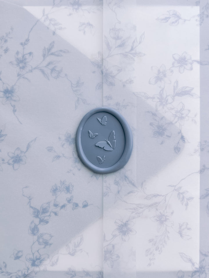 light blue 3D butterflies oval wax seal on a floral vellum wrap with blue botanical pattern