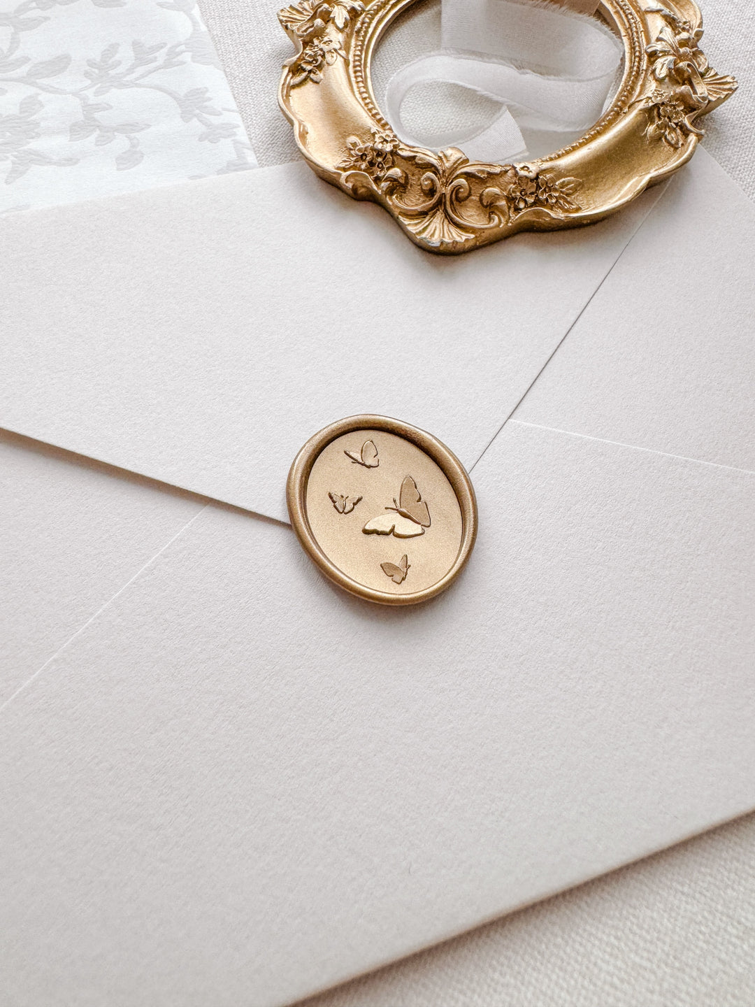 Light gold 3D butterflies oval wax seal on a beige envelope