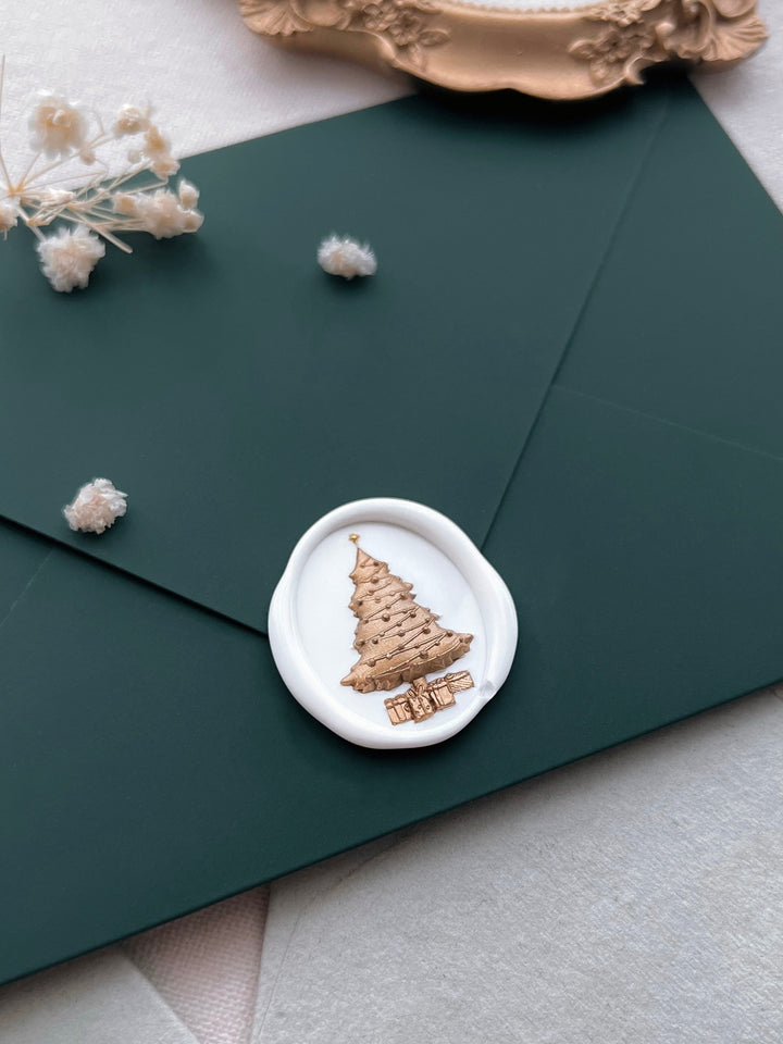 white and gold Christmas tree wax seal with 3D engraving on a dark green envelope
