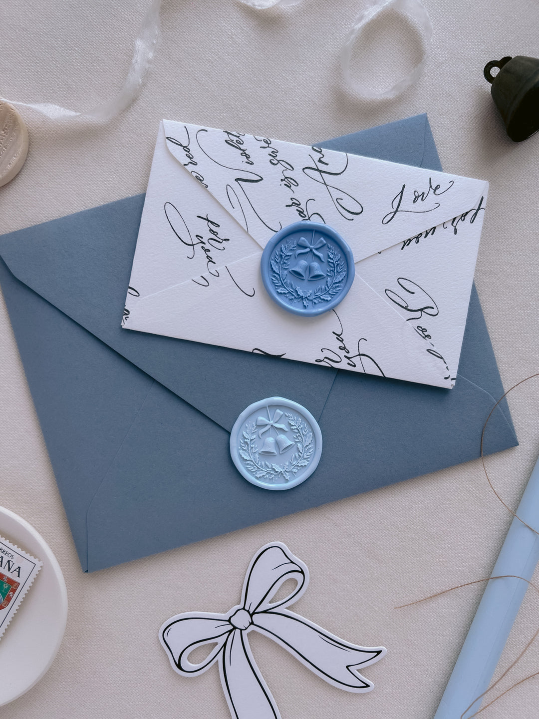 Blue and light blue 3D Christmas wreath and jingle bells wax seals on a dusty blue and  a mini script-patterned envelope
