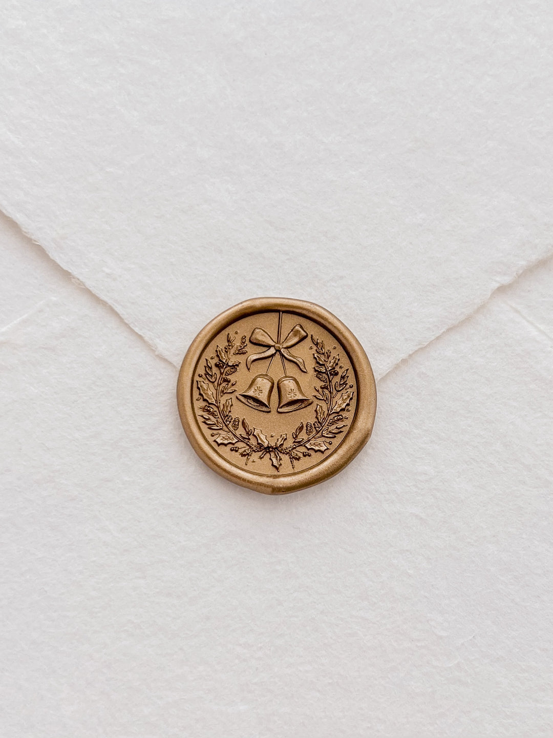 Gold 3D Christmas wreath and jingle bells wax seal on a white deckle-edge handmade paper envelope