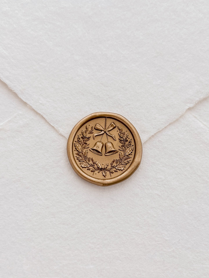 Gold 3D Christmas wreath and jingle bells wax seal on a white deckle-edge handmade paper envelope
