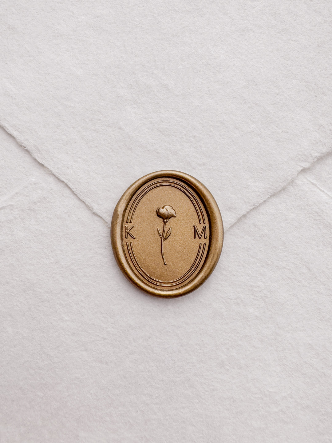 Personalized initials gold 3D flower oval wax seal featuring a custom monogram on a white deckled edge handmade paper envelope