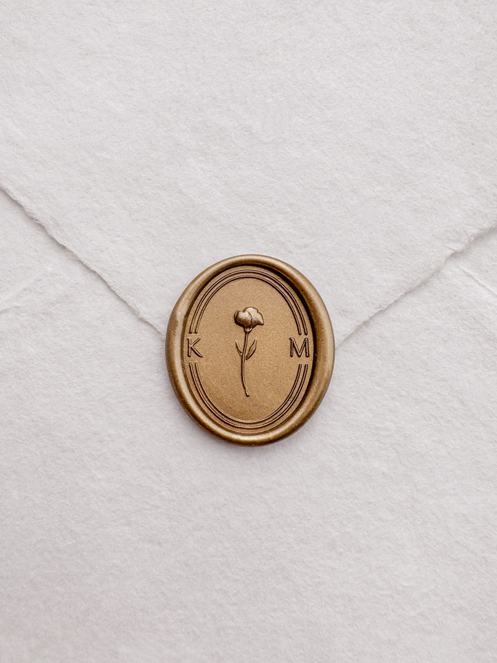Personalized initials gold 3D flower oval wax seal featuring a custom monogram on a white deckled edge handmade paper envelope
