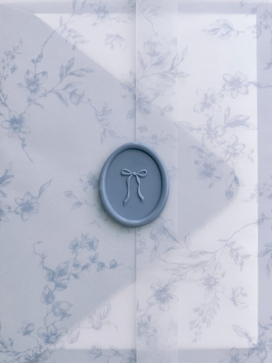 Dusty blue 3D hand-drawn ribbon bow oval wax seal on blue floral print vellum wrap