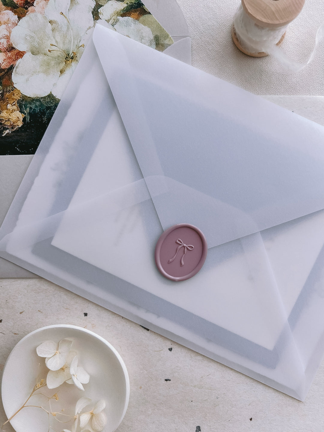 Mauve 3D hand-drawn ribbon bow oval wax seal on a vellum wedding invitation envelope 