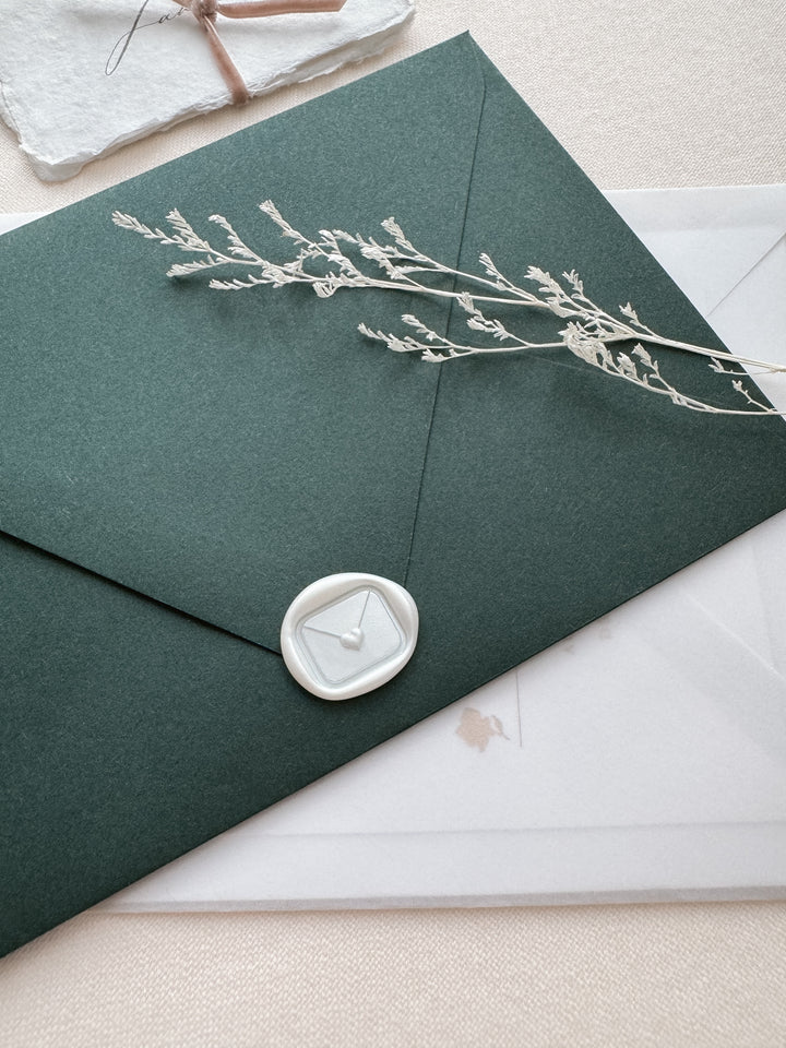 White mini heart sealed envelope wax seal on a dark green envelope