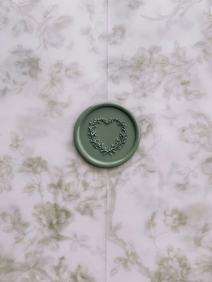 Sage green heart shaped leaf wreath wax seal on a green floral vellum jacket 