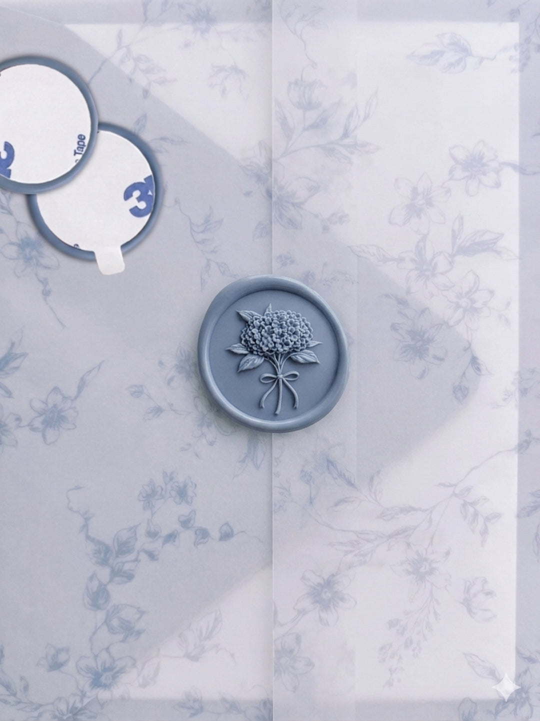 Dusty blue hydrangea bouquet floral wax seal stickers with self-adhesive backings on a blue floral print vellum jacket 