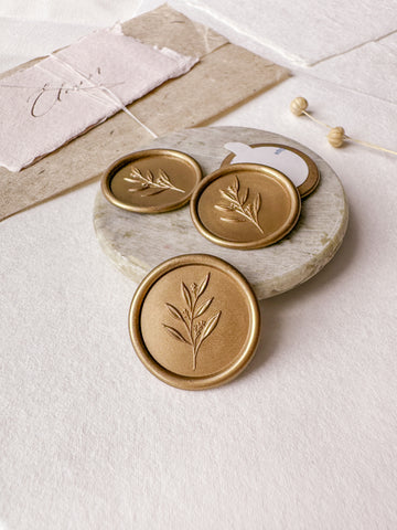 Leaf branch gold wax seals with 3D engraving styled with a small gray stone dish, handmade paper and a dried floral branch