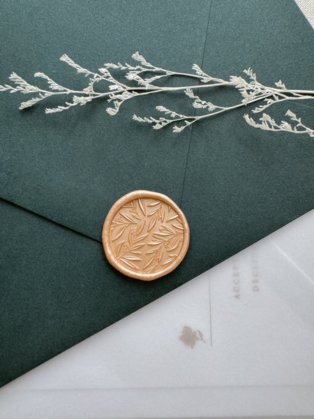 3D leaf pattern gold wax seal on a dark green envelope