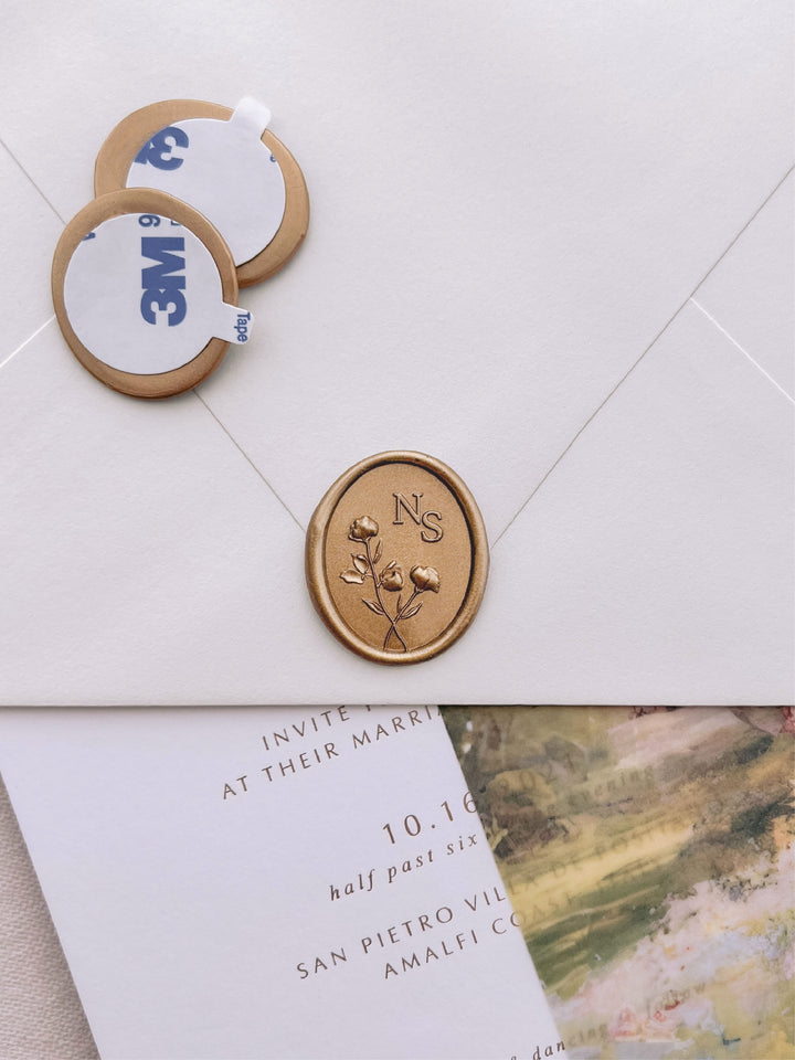 Custom 3D floral monogram oval gold wax seal stickers with self-adhesive backings on a wedding invitation, beige envelope, and vellum jacket