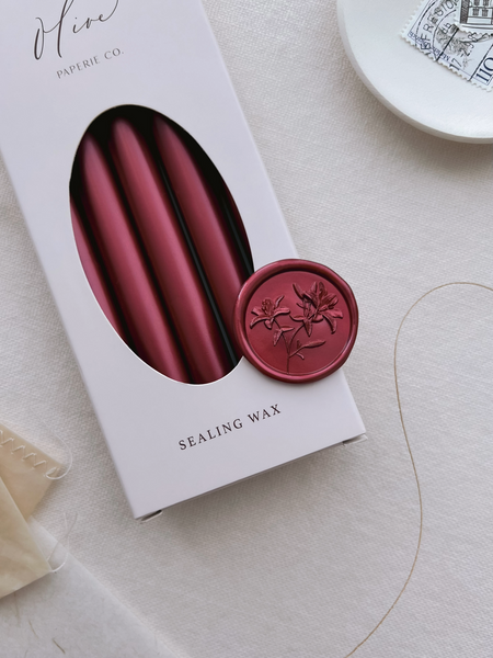 dark metallic red lilies floral wax seal on a box of metallic red sealing wax sticks