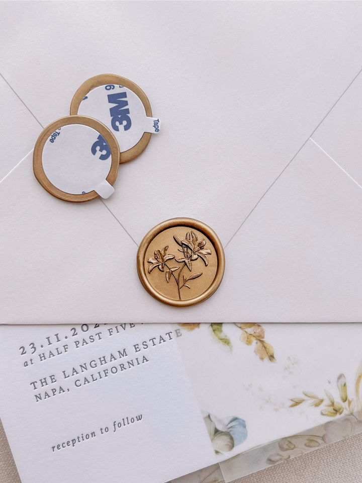 Gold 3D lilies floral wax seal stickers with self-adhesive backings on a wedding invitation, beige envelope, and floral vellum jacket
