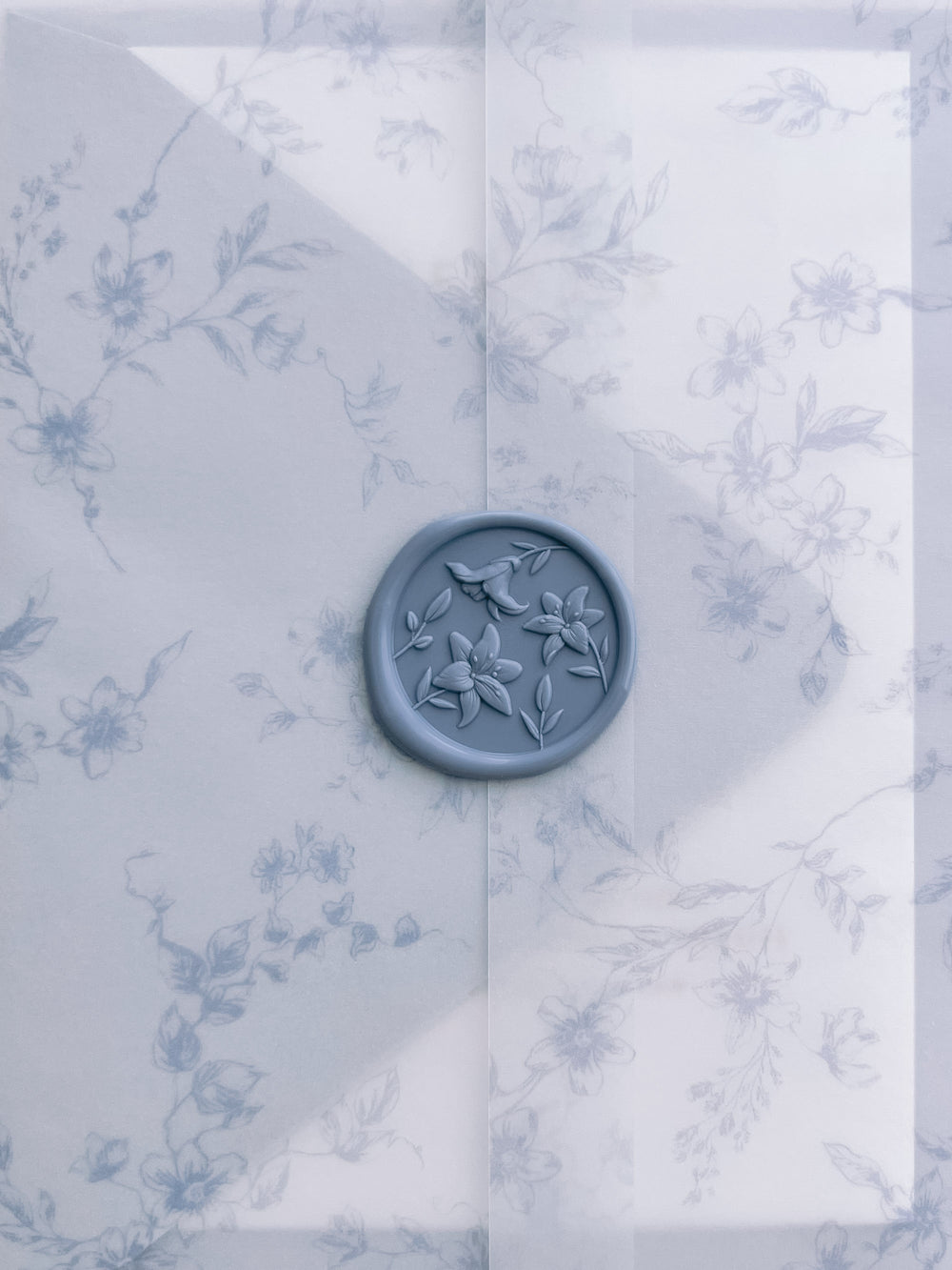 dusty blue 3D lily blossom wax seal on a blue floral print vellum jacket 