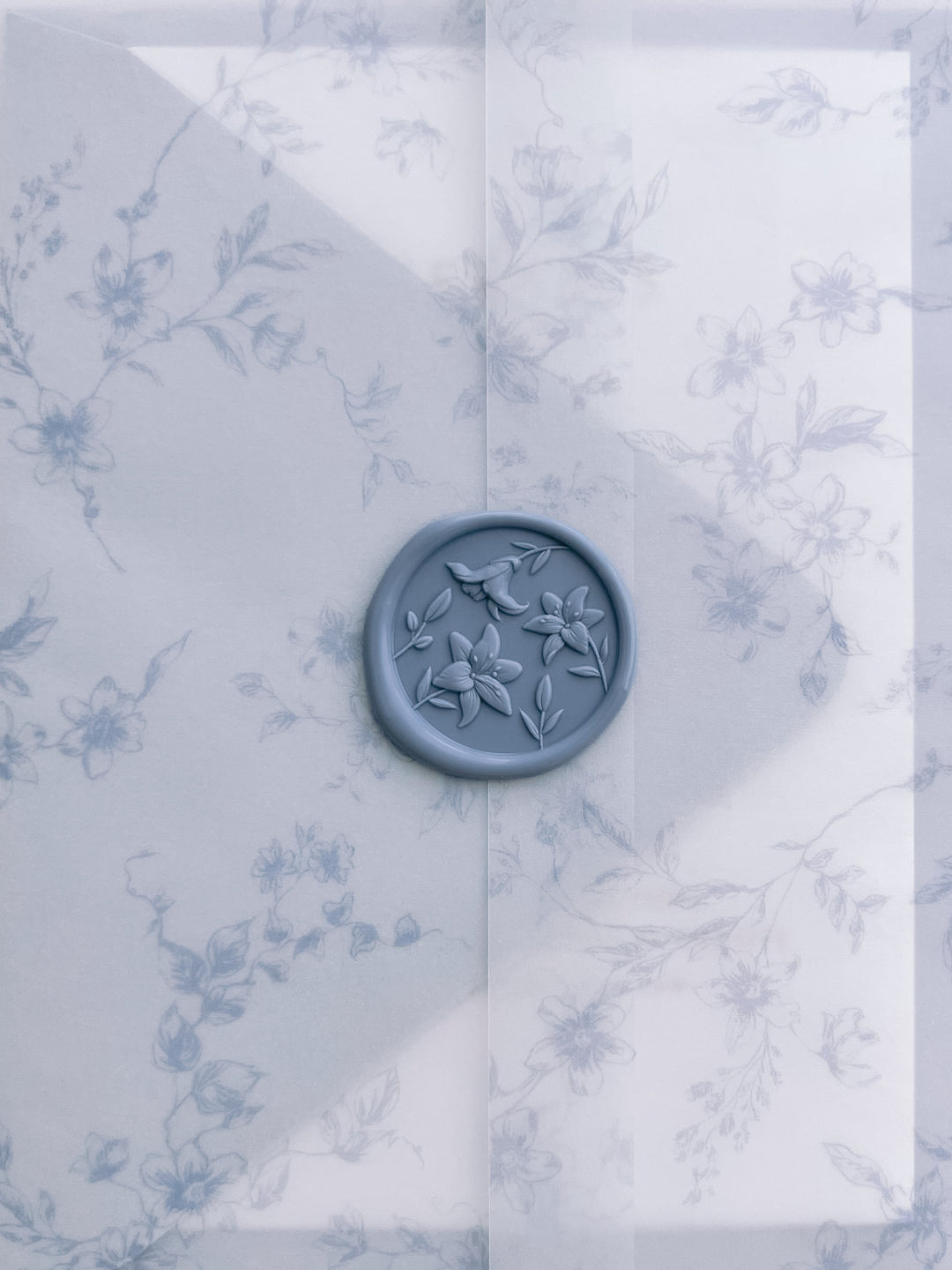 dusty blue 3D lily blossom wax seal on a blue floral print vellum jacket 