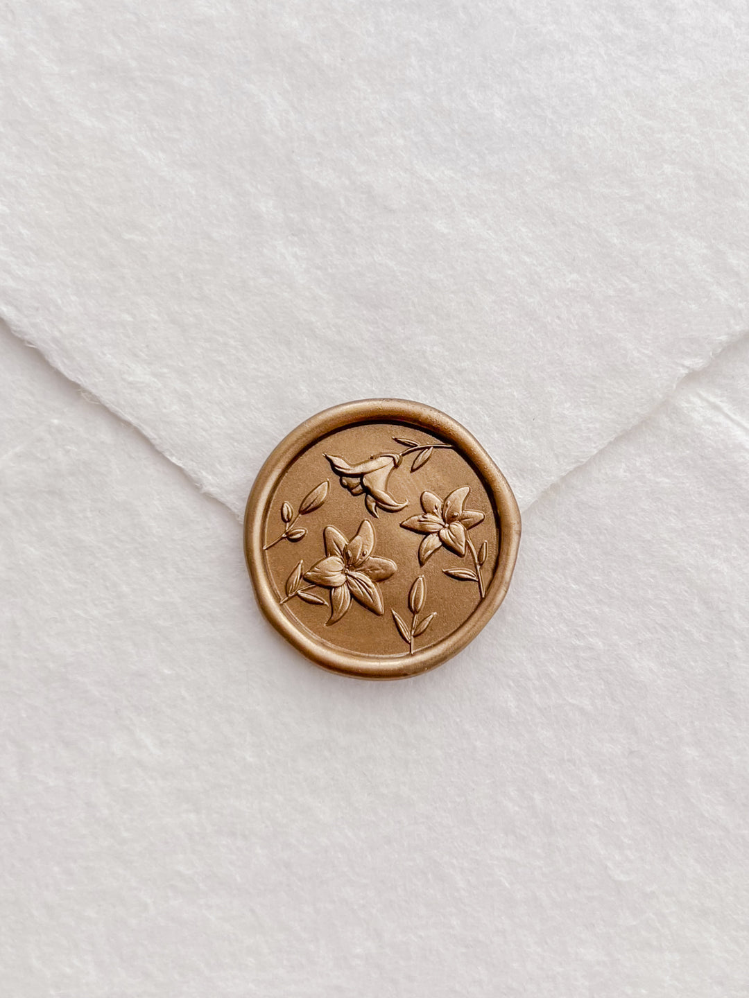 gold 3D lily bloom wax seal on a white textured handmade paper envelope