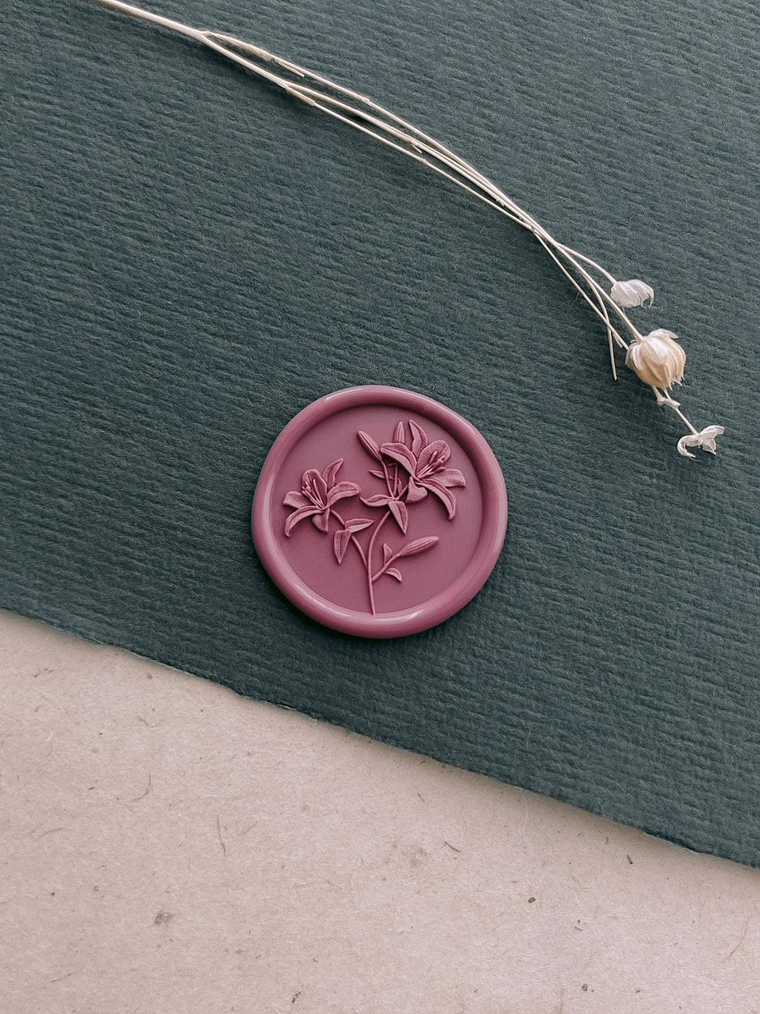 Rose pink 3D lily blossom wax seal on a dark green textured paper 