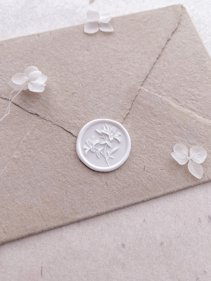 Lily floral wax seal on a beige envelope and small white flowers on a light background
