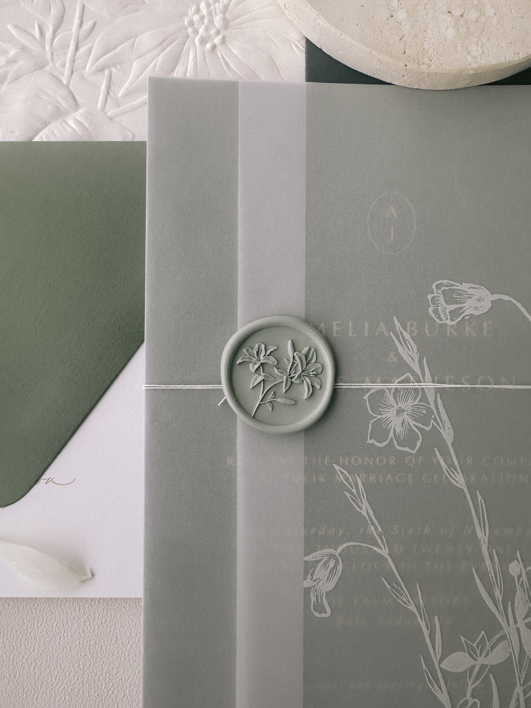 Light sage green 3D lily wax seal on a floral vellum wrap over ab olive green wedding invitation card