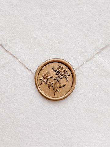 Gold lily floral seal on a white envelope