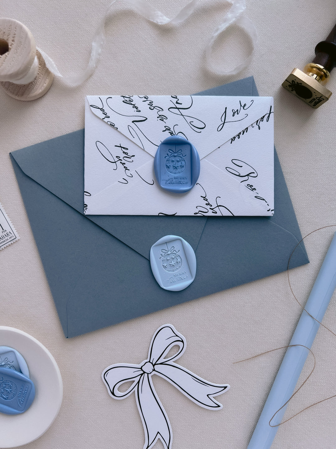 blue and light blue Merry Christmas ornament design wax seals on dusty blue and white envelopes styled with festive props