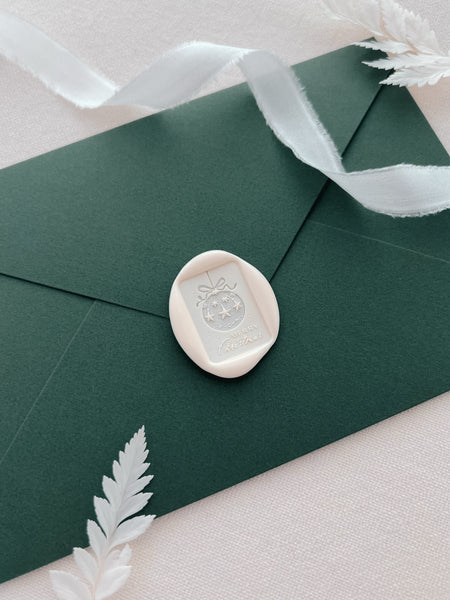 white festive design envelope wax seal with an ornament and the phrase Merry Christmas