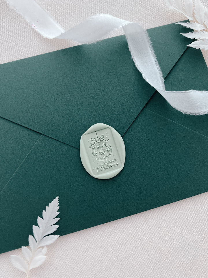 light sage green festive design envelope wax seal featuring an ornament and the phrase Merry Christmas
